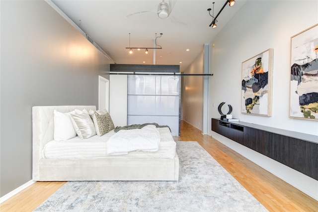 bedroom with ceiling fan, light hardwood / wood-style floors, and rail lighting