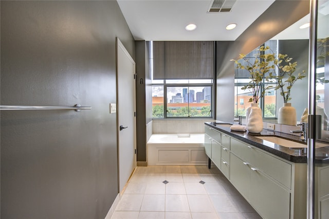 bathroom with a washtub, vanity, a healthy amount of sunlight, and tile patterned flooring