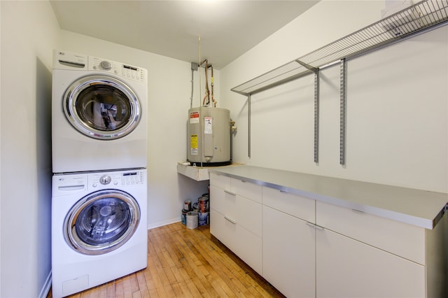 laundry area with cabinets, electric water heater, stacked washing maching and dryer, and light hardwood / wood-style floors