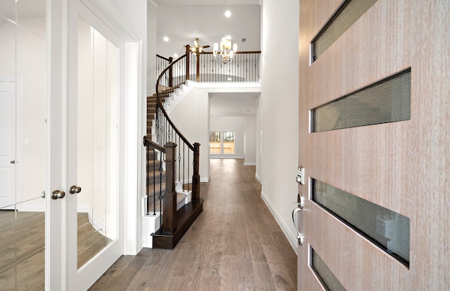 hall with hardwood / wood-style floors, a towering ceiling, a chandelier, and french doors