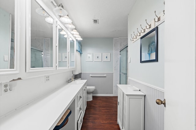 bathroom featuring wood walls, hardwood / wood-style floors, toilet, a shower with door, and vanity