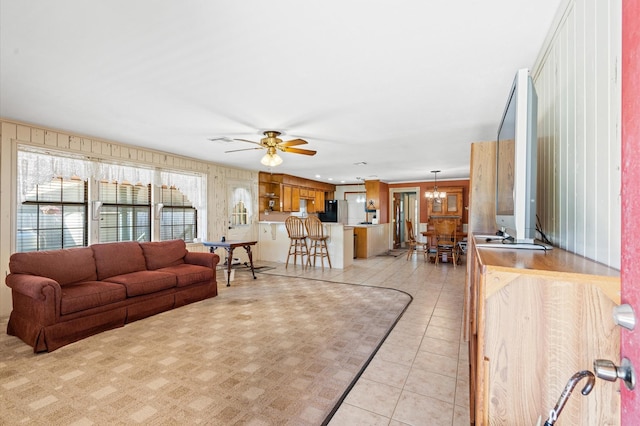 living room with ceiling fan with notable chandelier and light tile patterned floors