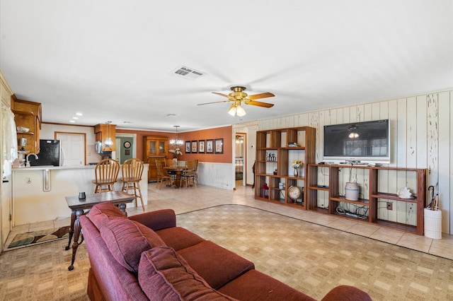 tiled living room with ceiling fan and ornamental molding