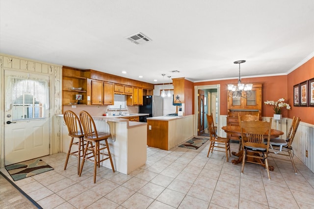 kitchen with pendant lighting, a breakfast bar, a notable chandelier, kitchen peninsula, and stainless steel refrigerator