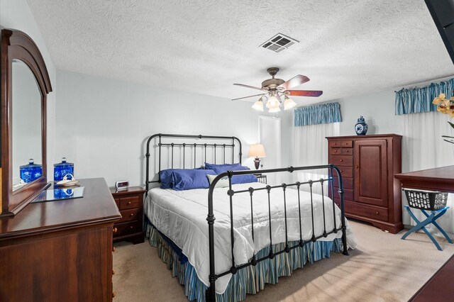 carpeted bedroom featuring ceiling fan and a textured ceiling