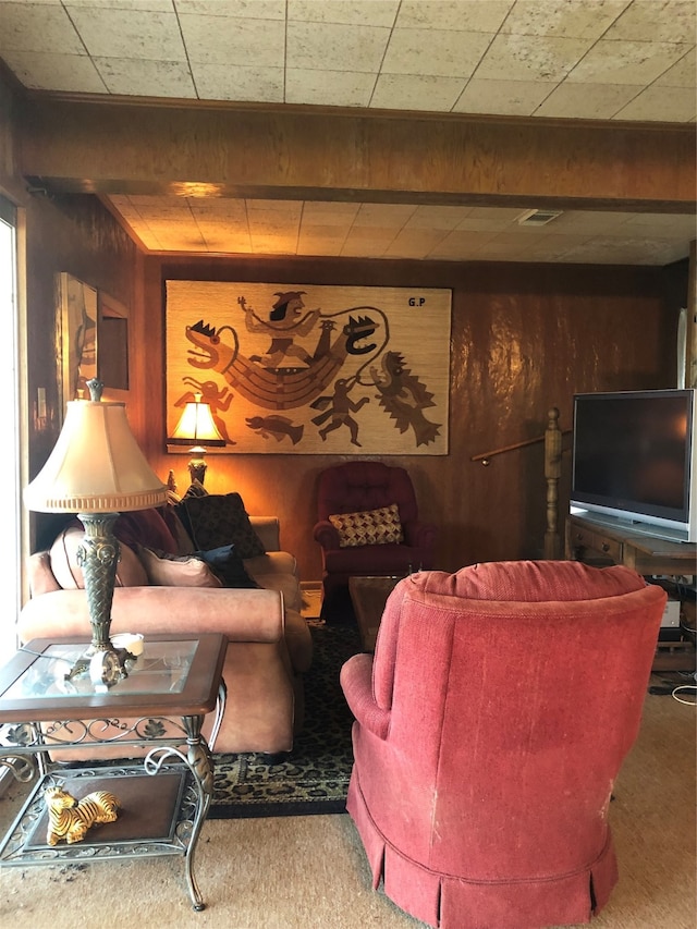 living room featuring carpet flooring, beam ceiling, and wood walls