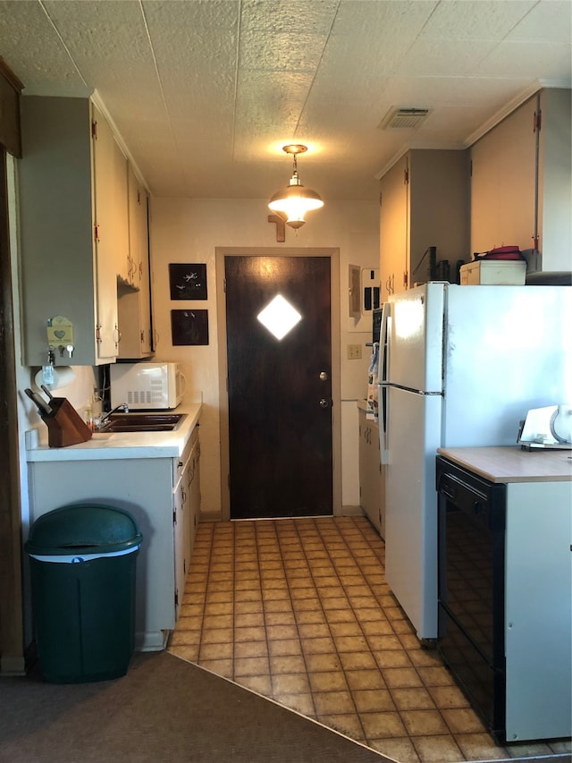 kitchen featuring light tile patterned floors, white appliances, and decorative light fixtures