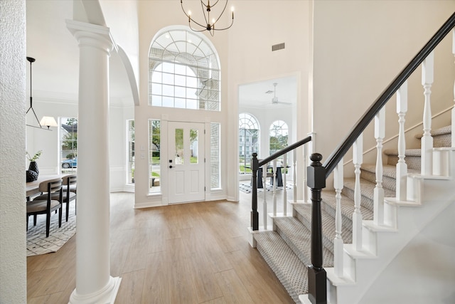 entrance foyer featuring a wealth of natural light, light hardwood / wood-style floors, ceiling fan with notable chandelier, and a high ceiling