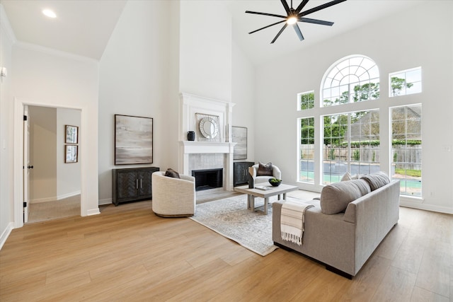 living room featuring ceiling fan, a high ceiling, and light wood-type flooring