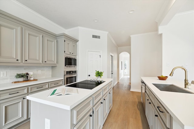 kitchen featuring sink, stainless steel appliances, light hardwood / wood-style floors, decorative backsplash, and a kitchen island