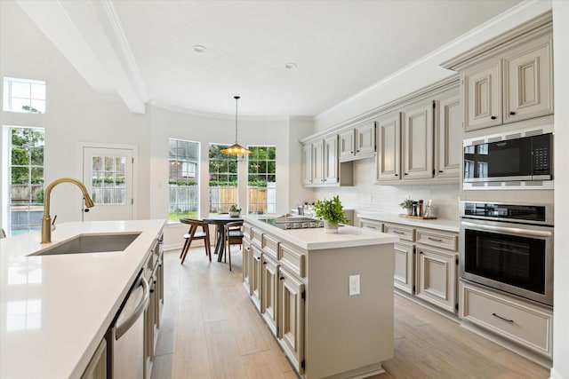 kitchen with appliances with stainless steel finishes, light wood-type flooring, backsplash, sink, and a center island