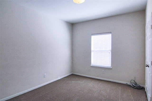 carpeted spare room featuring a healthy amount of sunlight and baseboards