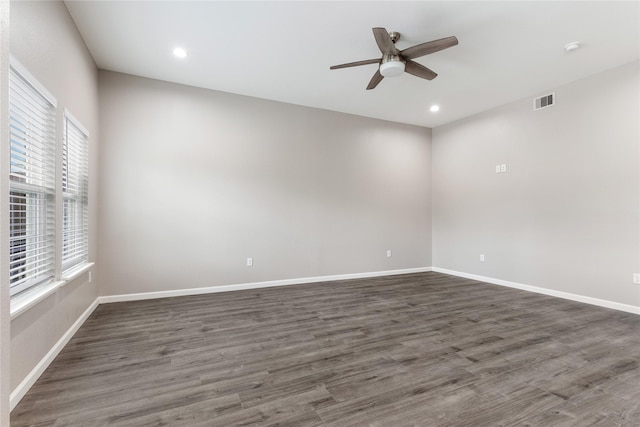 unfurnished room with dark wood-style floors, visible vents, and baseboards