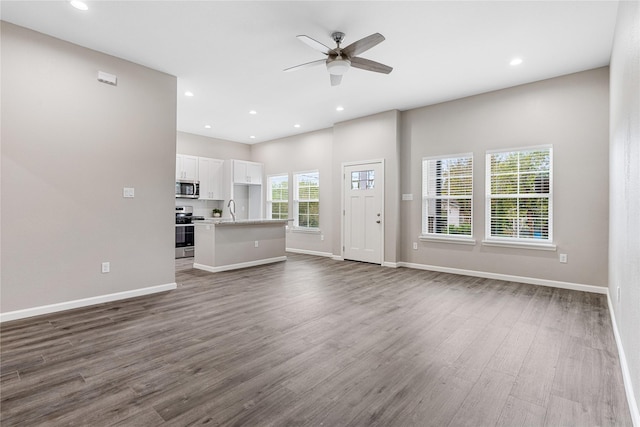 unfurnished living room featuring ceiling fan, baseboards, dark wood finished floors, and recessed lighting