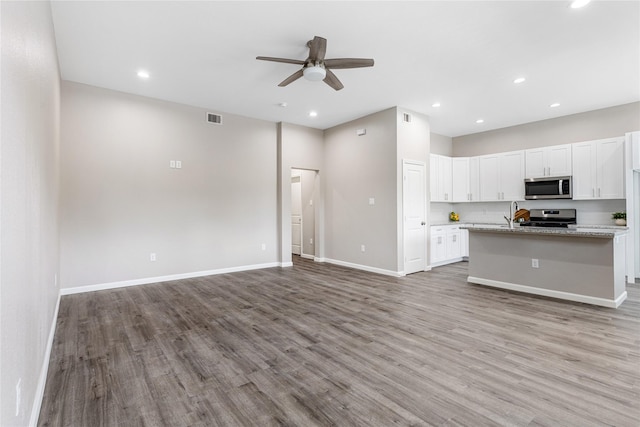 kitchen featuring light wood finished floors, visible vents, ceiling fan, open floor plan, and stainless steel appliances