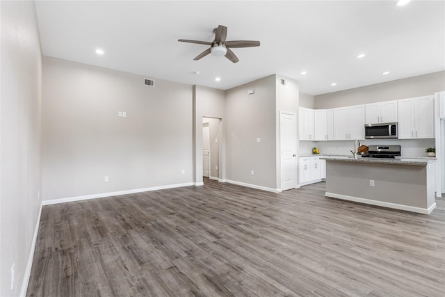 1319 E 35th St, Houston, TX 77022 - kitchen with stainless steel appliances, ceiling fan, open floor plan, light wood-style floors, and white cabinets