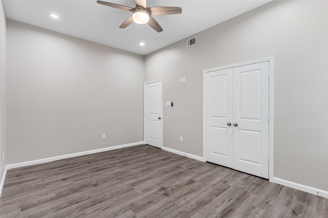 unfurnished bedroom featuring a closet, visible vents, ceiling fan, wood finished floors, and baseboards