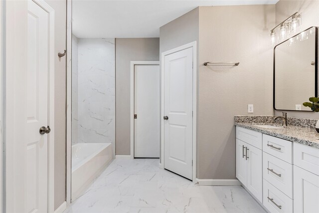 full bathroom with marble finish floor, a bathing tub, baseboards, and vanity