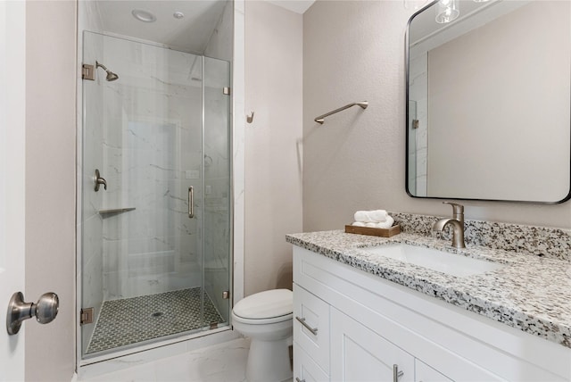 bathroom featuring a marble finish shower, vanity, and toilet