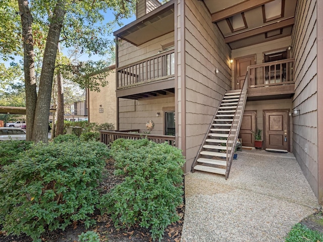 view of property exterior with stairs, a chimney, and a balcony