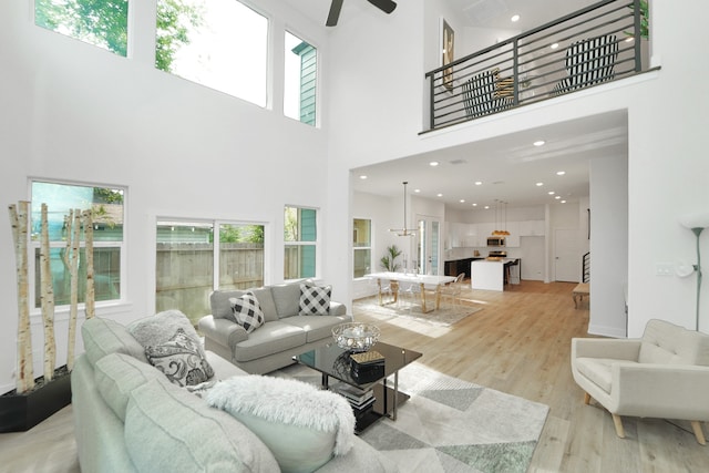 living room with plenty of natural light, a towering ceiling, and light hardwood / wood-style flooring