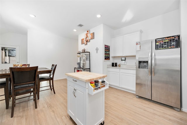 kitchen with wooden counters, stainless steel refrigerator with ice dispenser, light wood-type flooring, white cabinets, and a kitchen island