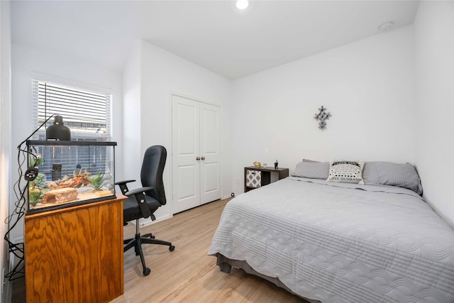 bedroom with light hardwood / wood-style floors and a closet