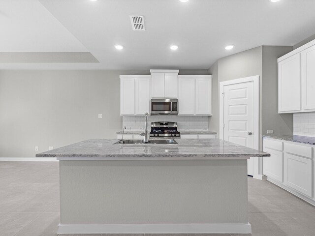 kitchen featuring light stone countertops, sink, an island with sink, and stainless steel appliances