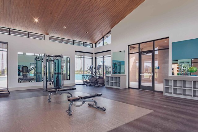 exercise room with dark wood-type flooring, high vaulted ceiling, and wooden ceiling