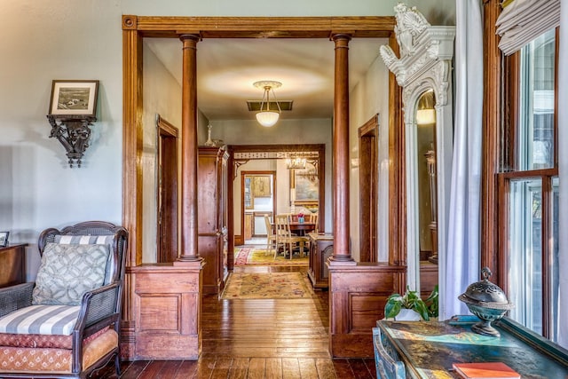 hallway featuring dark hardwood / wood-style flooring and decorative columns