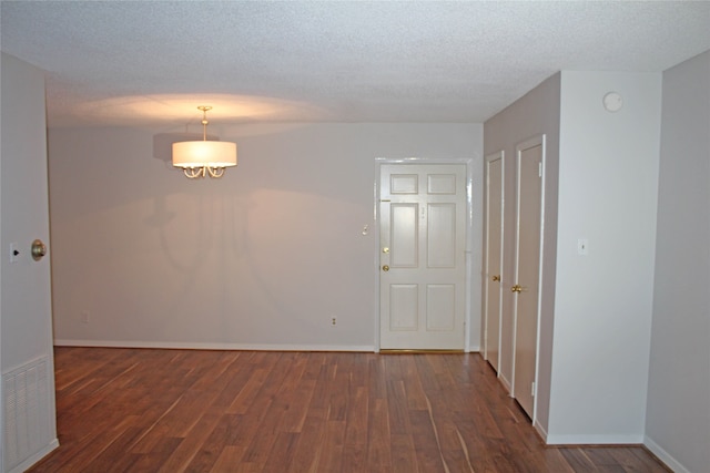 empty room with dark hardwood / wood-style flooring and a textured ceiling