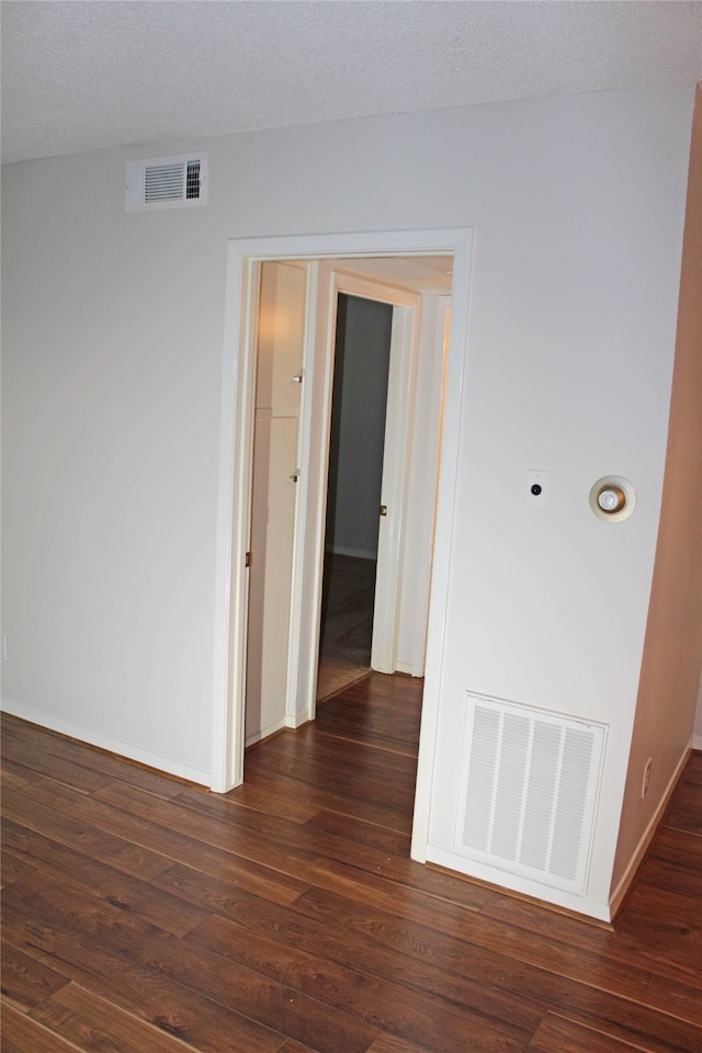 corridor featuring dark hardwood / wood-style flooring and a textured ceiling