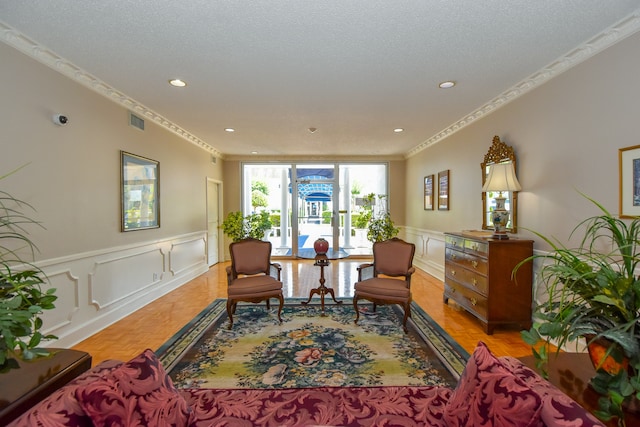 living area featuring a textured ceiling, crown molding, and light hardwood / wood-style flooring