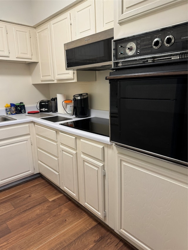 kitchen with sink, dark hardwood / wood-style floors, and black appliances