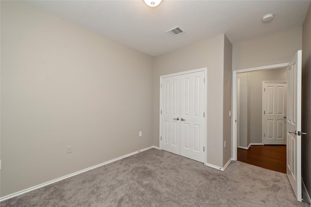 unfurnished bedroom featuring light carpet, a textured ceiling, and a closet