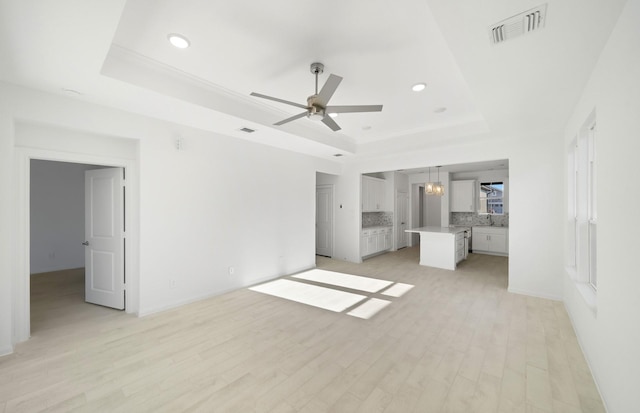 interior space featuring light wood-style flooring, a raised ceiling, visible vents, and recessed lighting