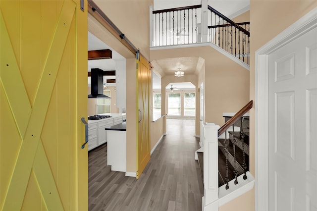 entrance foyer featuring ceiling fan, a barn door, light wood-type flooring, and a high ceiling