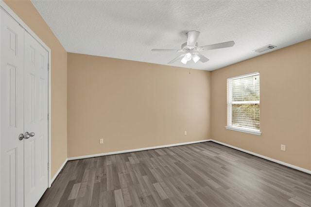 unfurnished bedroom with ceiling fan, wood-type flooring, a textured ceiling, and a closet