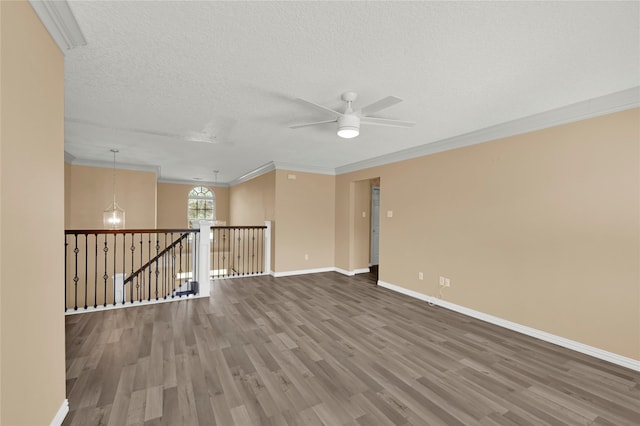 empty room featuring crown molding, ceiling fan, wood-type flooring, and a textured ceiling