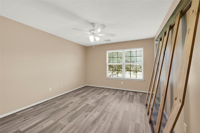 spare room with ceiling fan, a textured ceiling, and light hardwood / wood-style flooring