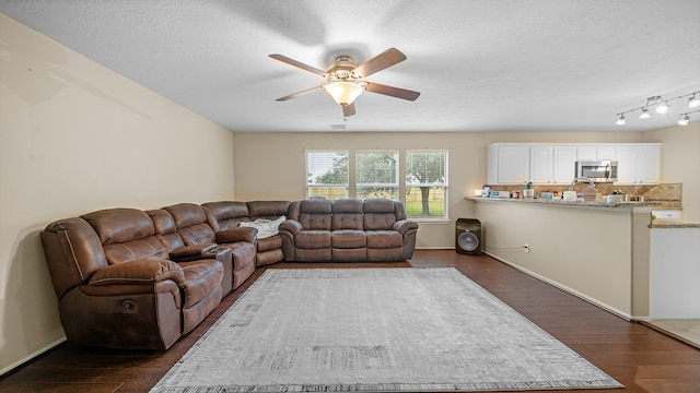 living room featuring dark hardwood / wood-style floors, ceiling fan, and a textured ceiling