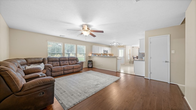 living room featuring ceiling fan, dark hardwood / wood-style flooring, and a textured ceiling