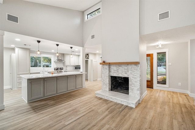 unfurnished living room with light hardwood / wood-style floors, a stone fireplace, and a towering ceiling