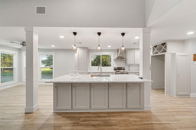 kitchen with gray cabinetry, a center island with sink, sink, electric range, and light stone countertops