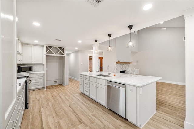 kitchen featuring white cabinets, a kitchen island with sink, sink, and appliances with stainless steel finishes