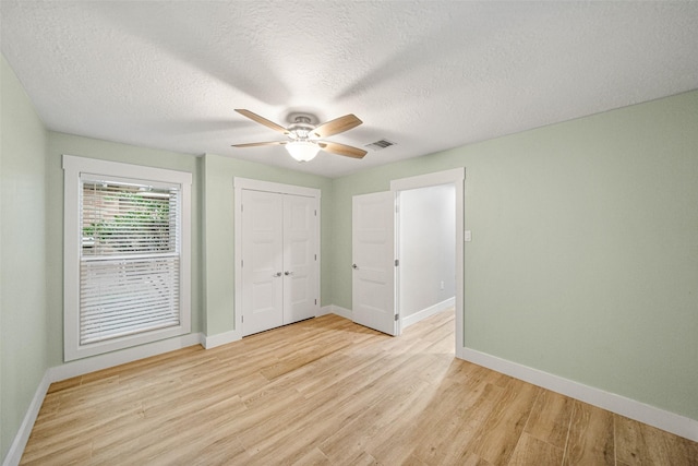 unfurnished bedroom featuring a closet, ceiling fan, light hardwood / wood-style flooring, and a textured ceiling