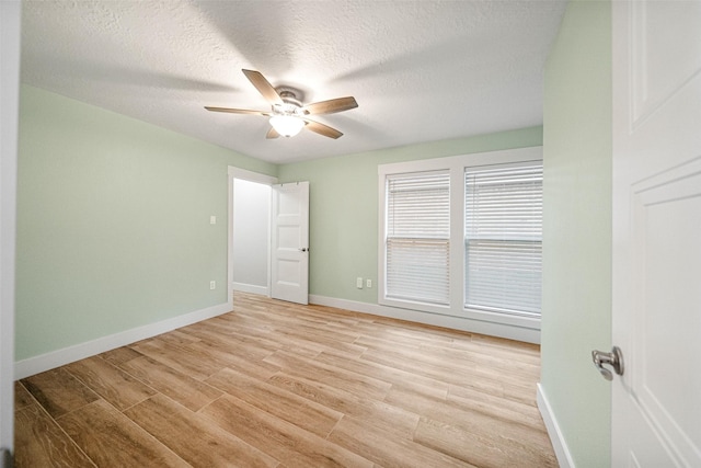 unfurnished room with ceiling fan, a textured ceiling, and light wood-type flooring