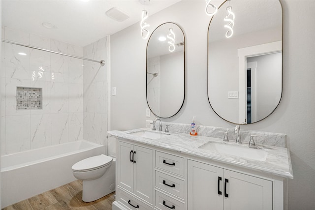 full bathroom with hardwood / wood-style floors, vanity, toilet, and tiled shower / bath