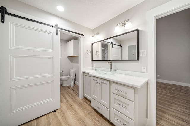 bathroom with hardwood / wood-style floors, vanity, toilet, and a textured ceiling