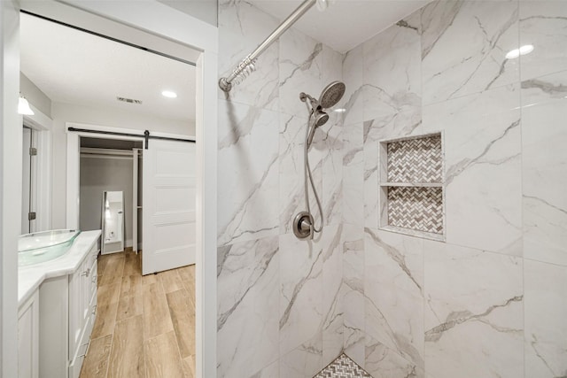 bathroom with a tile shower and vanity